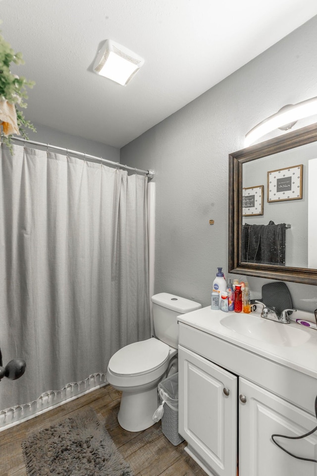 bathroom featuring toilet, a shower with curtain, wood finished floors, and vanity