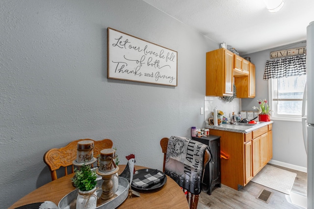 kitchen with light countertops, light wood-type flooring, visible vents, and baseboards