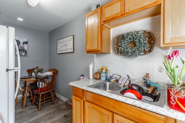 kitchen featuring freestanding refrigerator, light countertops, a sink, and backsplash