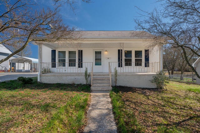 bungalow-style home featuring a carport, covered porch, and fence