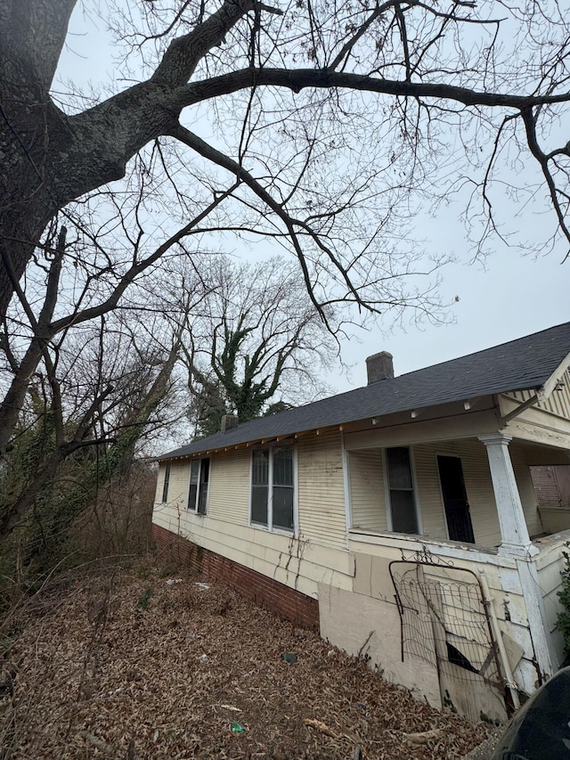 view of property exterior with roof with shingles and a chimney