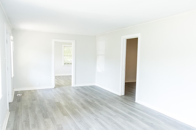 spare room featuring baseboards and light wood-style floors