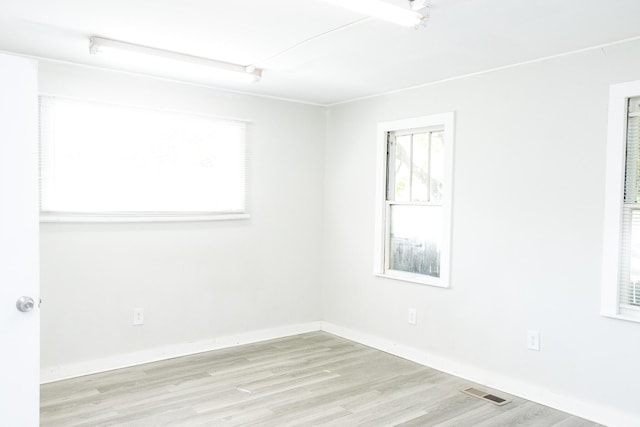 empty room featuring wood finished floors, visible vents, and baseboards