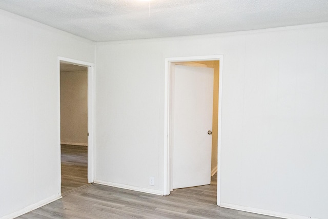 unfurnished room with a textured ceiling and wood finished floors