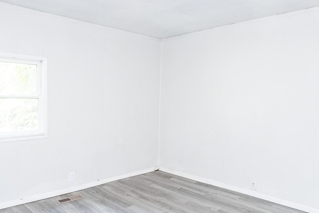 unfurnished room featuring visible vents, baseboards, and wood finished floors