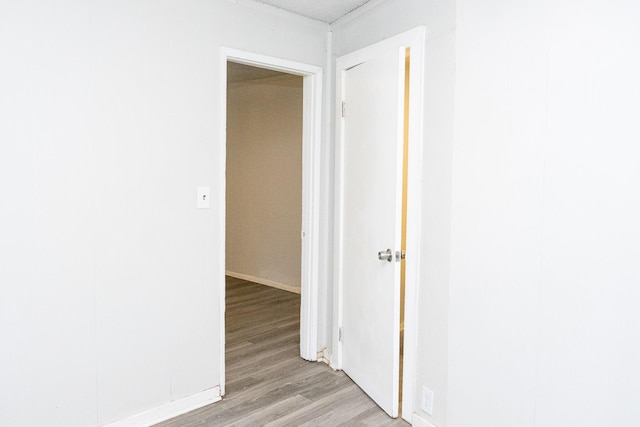 corridor with light wood-style flooring and baseboards