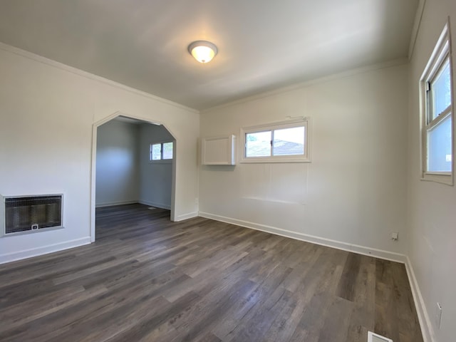 unfurnished room featuring dark wood-style floors, a glass covered fireplace, a healthy amount of sunlight, and heating unit