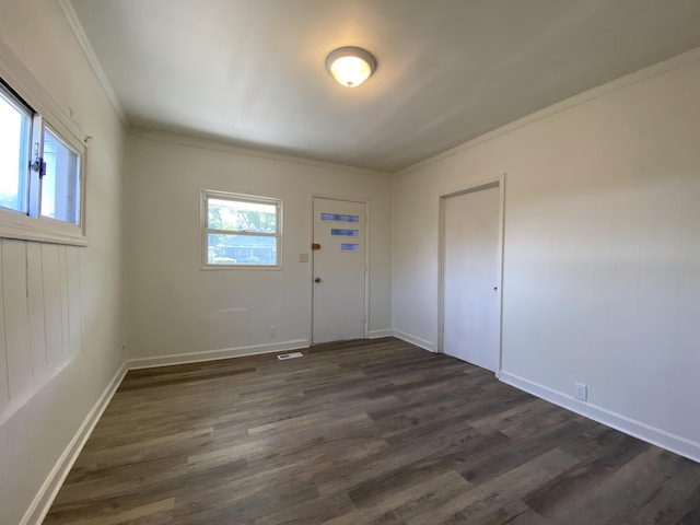 unfurnished room featuring plenty of natural light, dark wood-type flooring, and crown molding