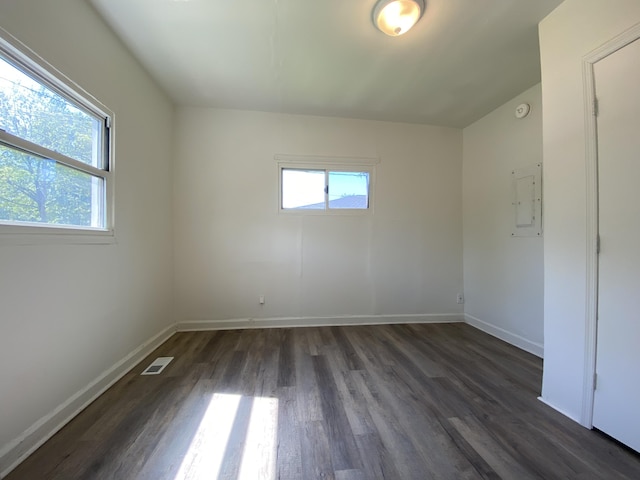 spare room with dark wood-type flooring, electric panel, visible vents, and baseboards