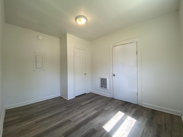 unfurnished bedroom with dark wood-type flooring, electric panel, and baseboards