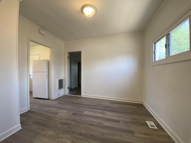 unfurnished room with dark wood-style flooring, visible vents, crown molding, and baseboards