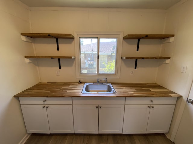 kitchen featuring open shelves, butcher block counters, a sink, and white cabinetry