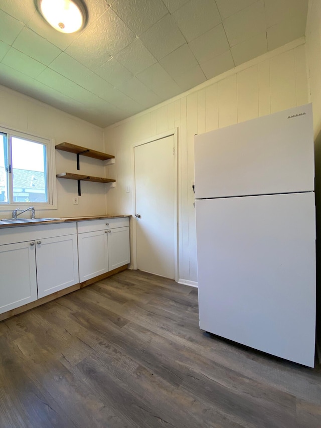 kitchen with a sink, white cabinetry, freestanding refrigerator, open shelves, and dark wood finished floors