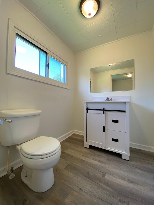 bathroom with toilet, baseboards, wood finished floors, and vanity