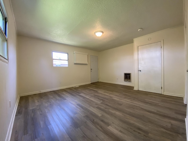 unfurnished room featuring dark wood-style flooring, baseboards, a textured ceiling, and heating unit