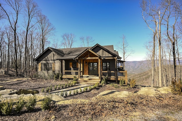 view of front facade with roof with shingles, a porch, and board and batten siding