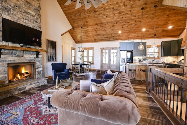 living room featuring a fireplace, dark wood-type flooring, high vaulted ceiling, wooden ceiling, and baseboards