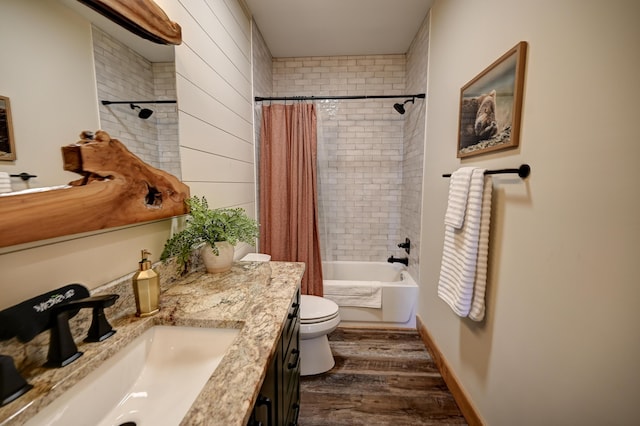 bathroom featuring toilet, shower / bath combo with shower curtain, vanity, wood finished floors, and baseboards