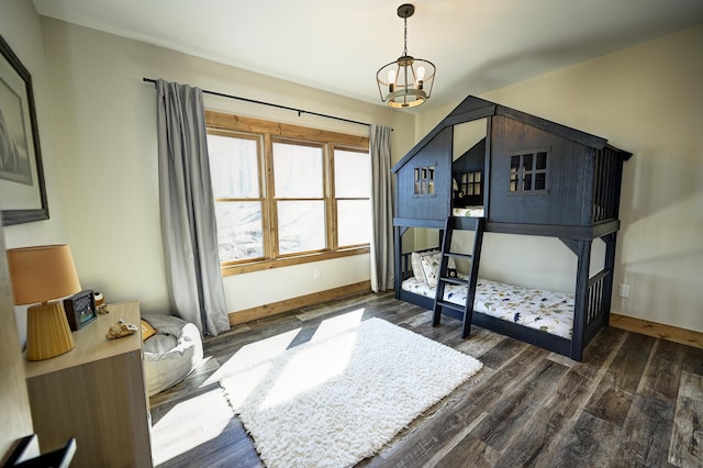 bedroom with a notable chandelier, dark wood finished floors, and baseboards