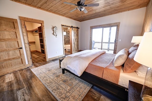 bedroom with a barn door, wooden ceiling, wood finished floors, baseboards, and a spacious closet