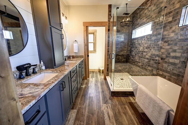 bathroom featuring a freestanding tub, wood finished floors, a sink, double vanity, and a stall shower