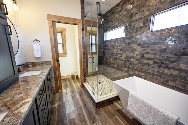 bathroom with a stall shower, a freestanding bath, wood finished floors, and vanity