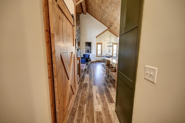 hallway with wooden ceiling, dark wood-style floors, a barn door, and high vaulted ceiling