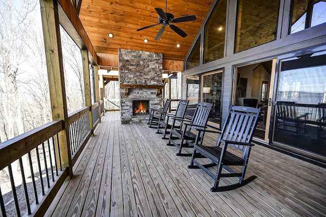 wooden deck with ceiling fan and an outdoor stone fireplace