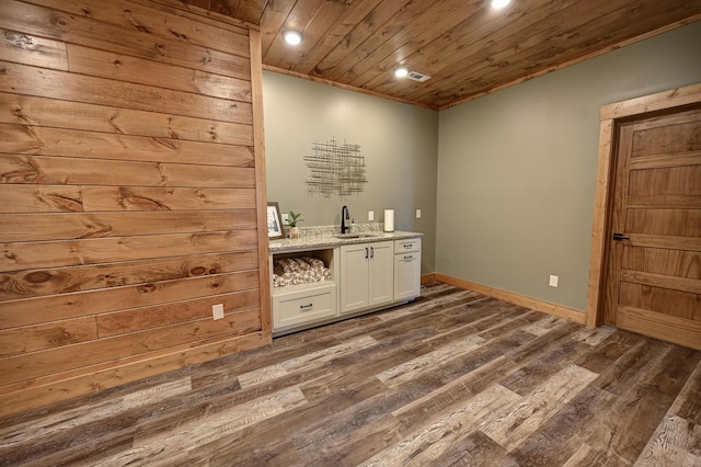 bar featuring wooden ceiling, a sink, baseboards, dark wood-style floors, and indoor wet bar