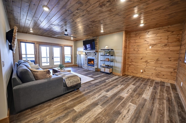 living area featuring ceiling fan, wood walls, a fireplace, wood finished floors, and wood ceiling