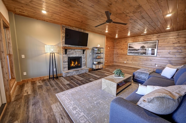 living room featuring recessed lighting, wood ceiling, wooden walls, a stone fireplace, and wood finished floors