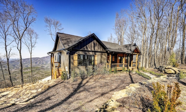 view of front facade featuring covered porch, a mountain view, board and batten siding, and roof with shingles