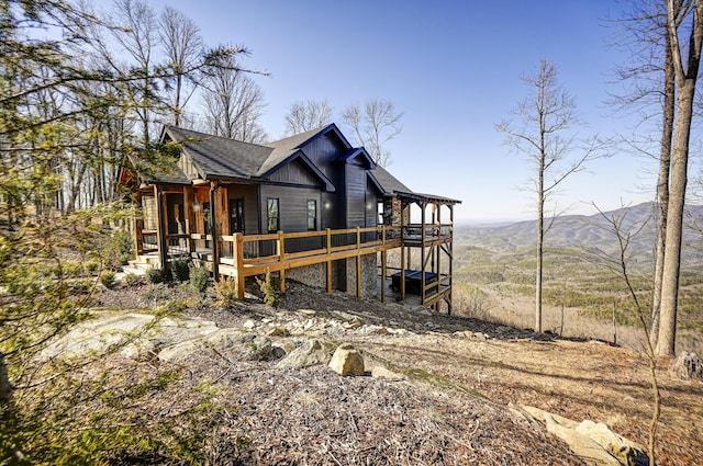 back of property featuring board and batten siding, a shingled roof, and a deck with mountain view