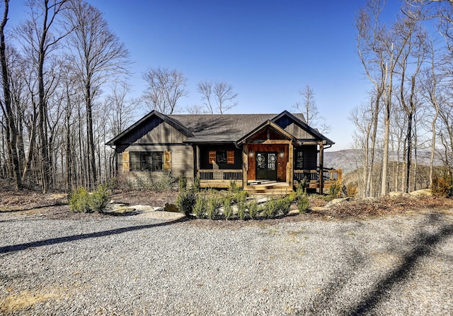 view of front of house with a porch, gravel driveway, and board and batten siding