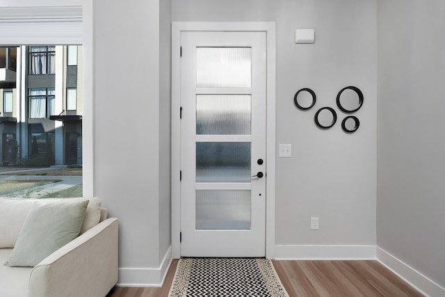doorway with baseboards and wood finished floors