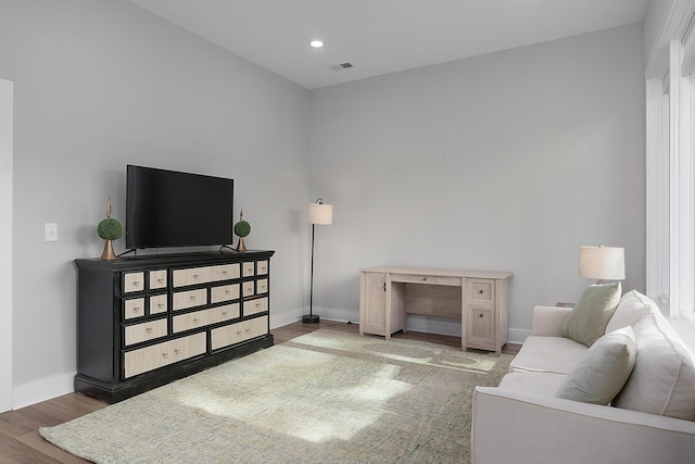 living room with recessed lighting, visible vents, baseboards, and wood finished floors