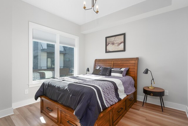 bedroom with baseboards, a chandelier, and light wood-style floors