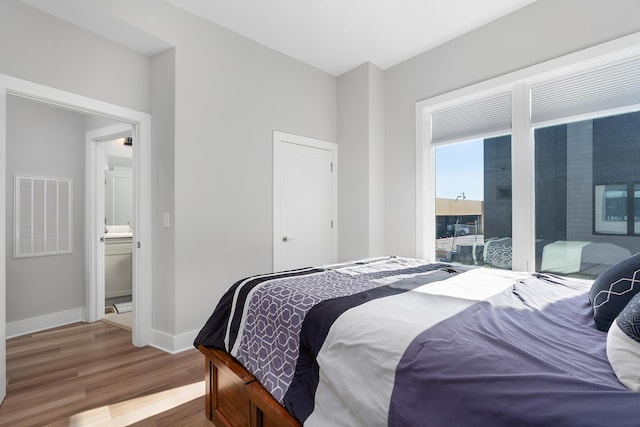 bedroom with baseboards, visible vents, and wood finished floors