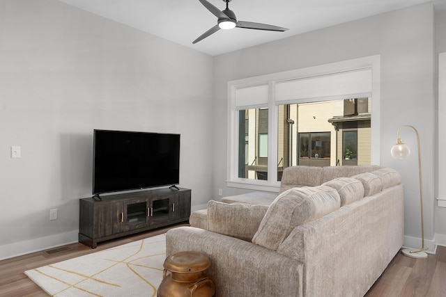 living area with baseboards, a ceiling fan, and wood finished floors