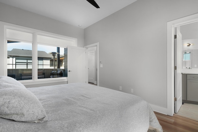 bedroom featuring ceiling fan, ensuite bath, and wood finished floors