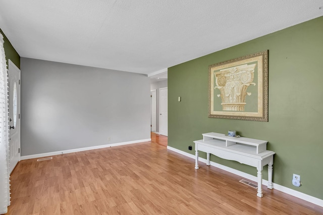 unfurnished room with baseboards, visible vents, and light wood-style floors