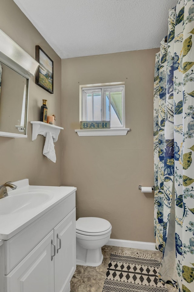 bathroom with a textured ceiling, toilet, vanity, baseboards, and tile patterned floors