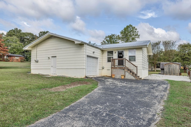 view of front facade featuring a garage, a front yard, metal roof, and aphalt driveway