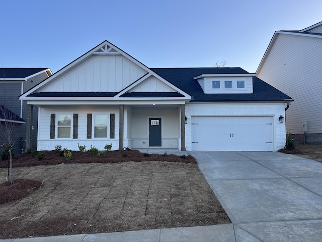 view of front of home with a porch, an attached garage, brick siding, concrete driveway, and board and batten siding