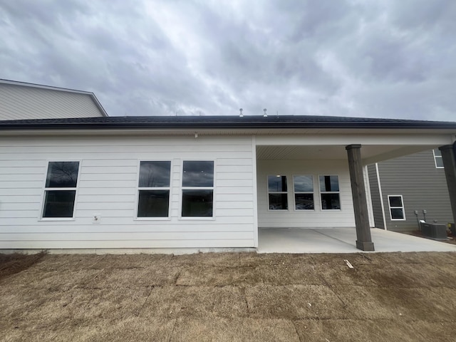 rear view of house featuring a lawn, cooling unit, and a patio