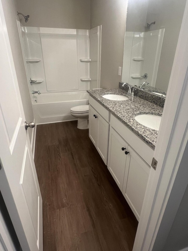 bathroom featuring a sink, bathtub / shower combination, wood finished floors, and toilet