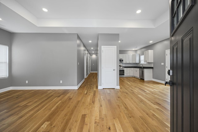 kitchen featuring light wood-style floors, appliances with stainless steel finishes, open floor plan, and white cabinets