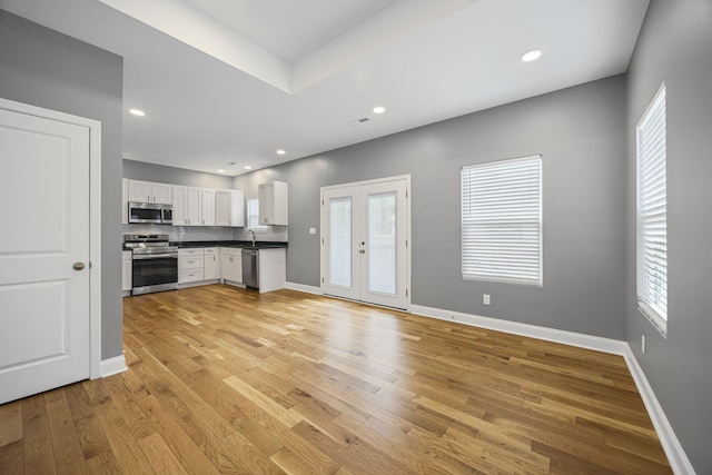 kitchen featuring dark countertops, baseboards, decorative backsplash, light wood-style floors, and stainless steel appliances