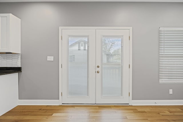 entryway with light wood finished floors, french doors, and baseboards