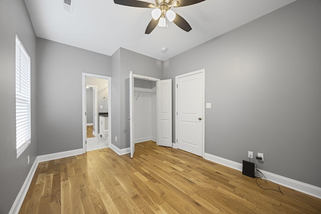 unfurnished bedroom with baseboards, light wood-type flooring, ensuite bathroom, and ceiling fan